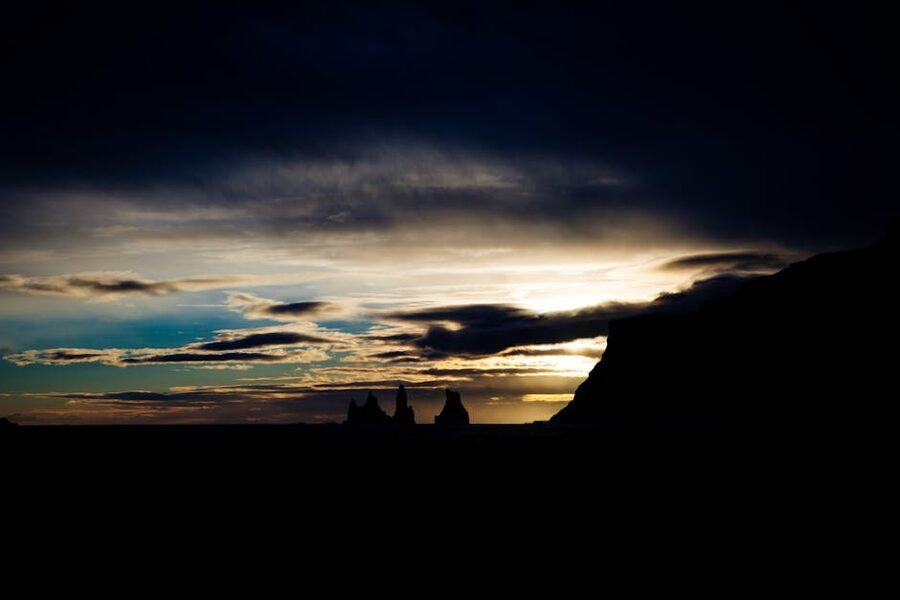 Reynisdrangar sea stacks silhouetted at twilight under midnight sun glow in Iceland