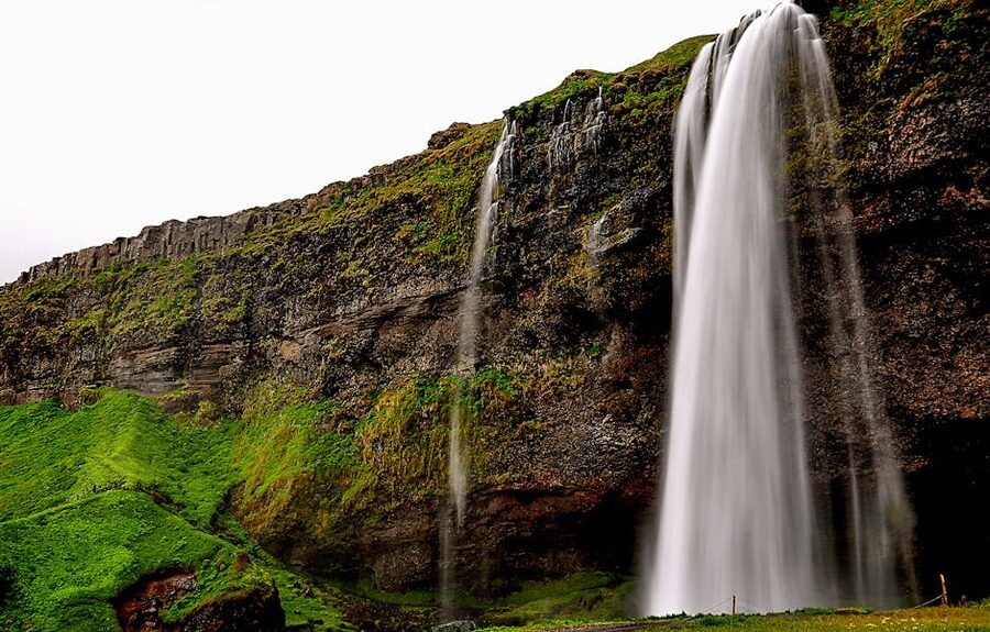 Seljalandsfoss waterfall flowing over green cliffs in Iceland