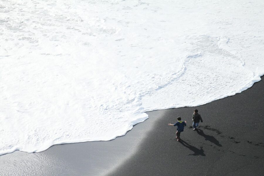 Two kids running near the surf at Reynisfjara black sand beach in Iceland