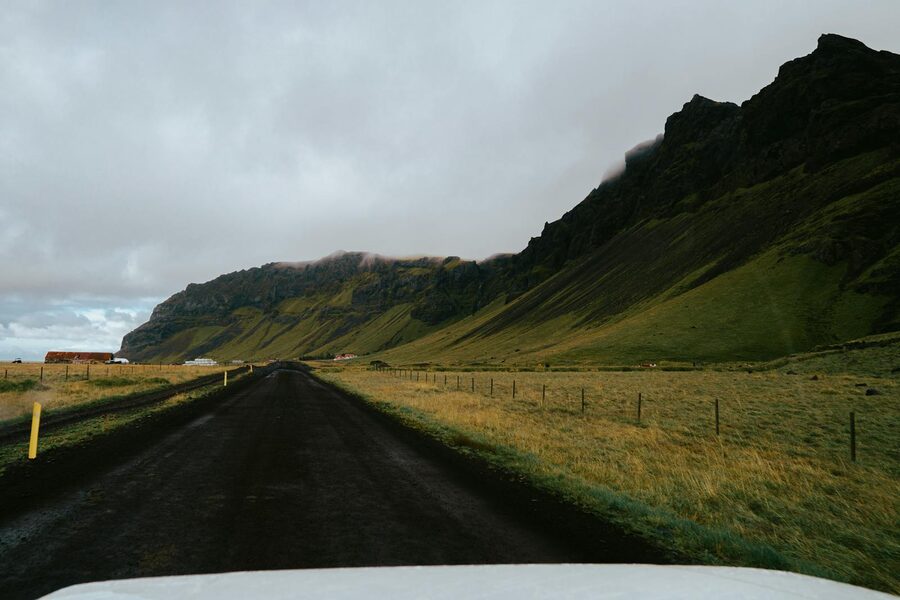 An empty road winds through green Icelandic mountains