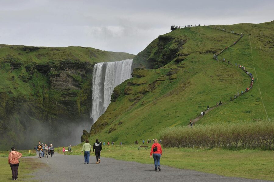 Visitors walking up the staircase at Skogafoss waterfall