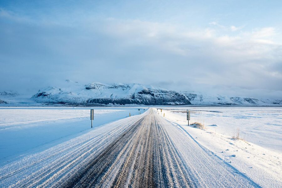 Snowy road heading toward distant mountains in winter Iceland