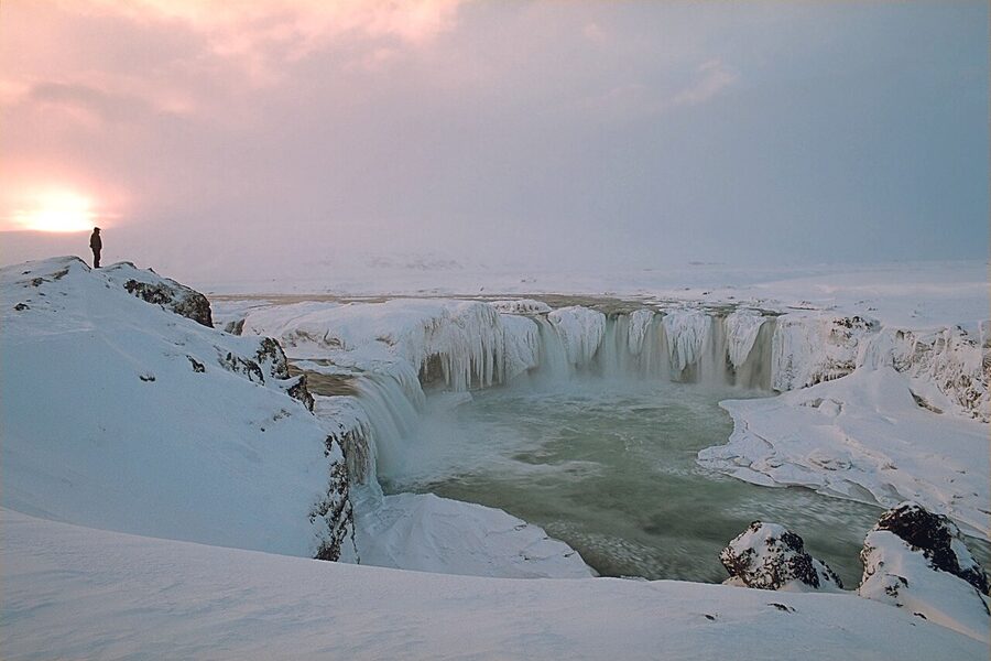 Sunset over Godafoss waterfall in winter with snow on the rocks