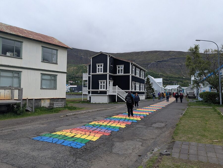 Rainbow painted street leading to the blue church in Seydisfjordur