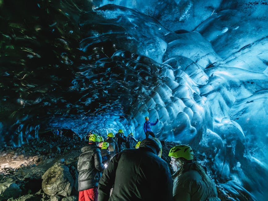 Tour group exploring an Iceland ice cave with helmets and headlamps