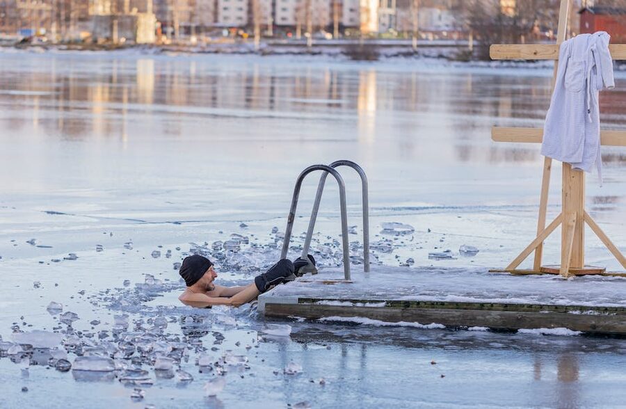Person stepping out of an icy cold plunge pool in winter