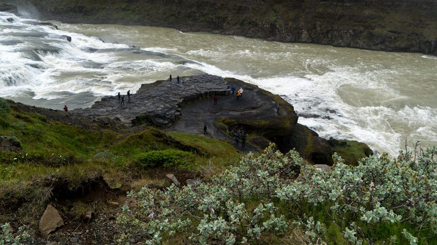 Gullfoss waterfall in Iceland with tourists on rocky ledge