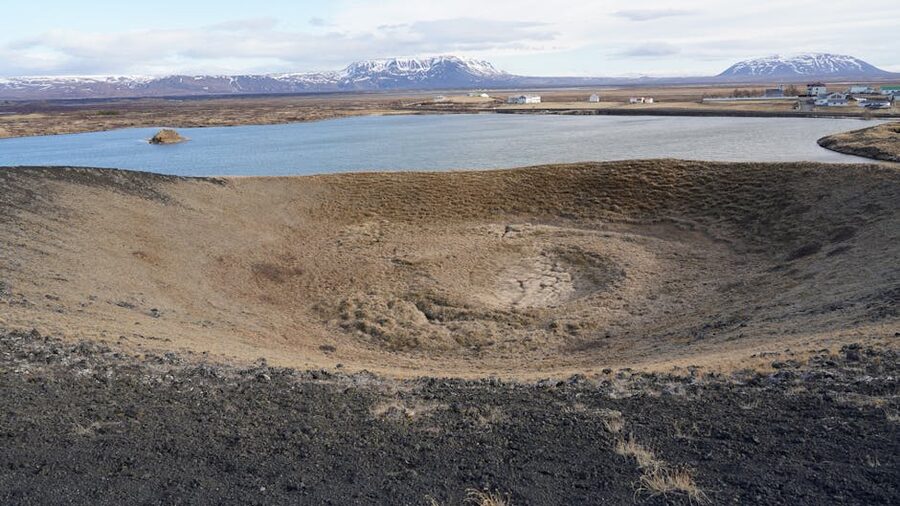 Volcanic crater and lake in Iceland with mountainous backdrop near Myvatn