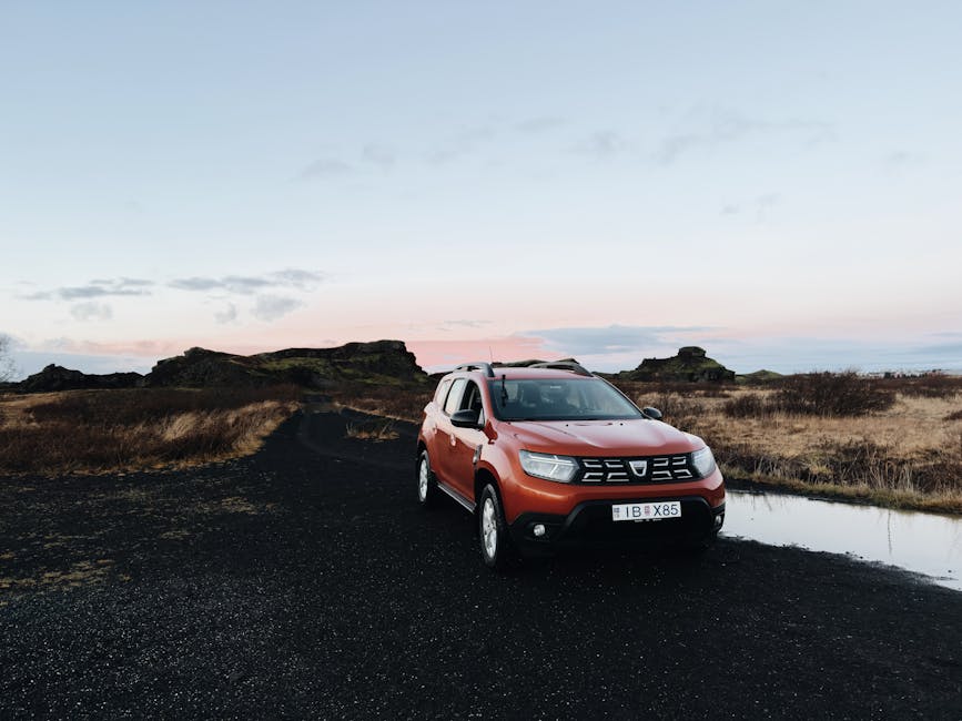 Orange SUV parked on dirt road in Iceland countryside at sunset