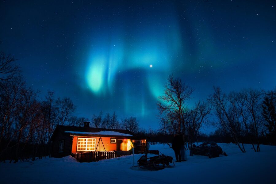 Aurora borealis over snowy cabin Iceland