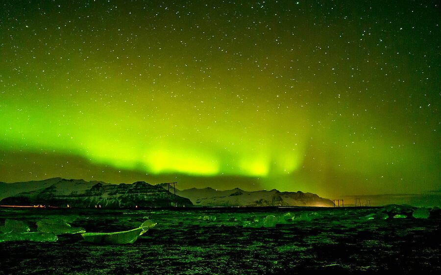 Green aurora arching over the ice chunks at Jökulsárlón Diamond Beach