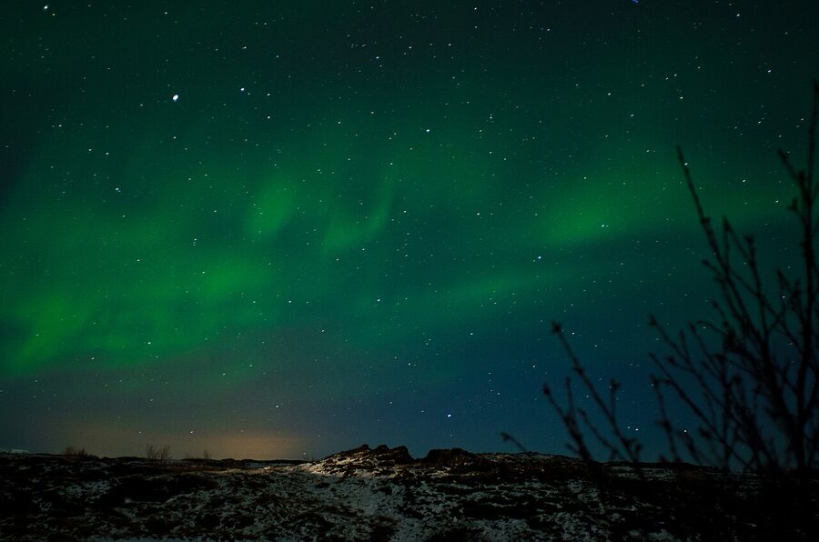 Aurora curtain dancing over a snow-dusted Iceland landscape on a clear winter night