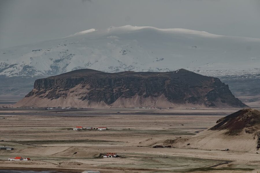 Snow-dusted Icelandic mountains under a moody sky, summit trail terrain