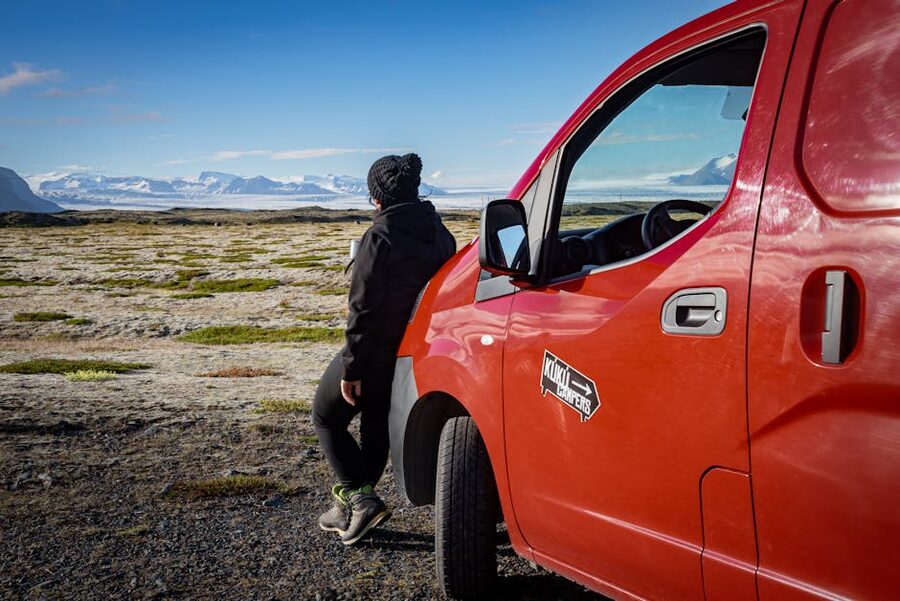 Traveler at a red campervan with mountains in Iceland