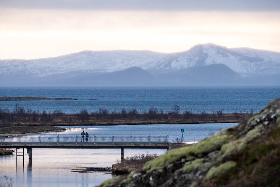 A peaceful Icelandic vista featuring a bridge water and mountains