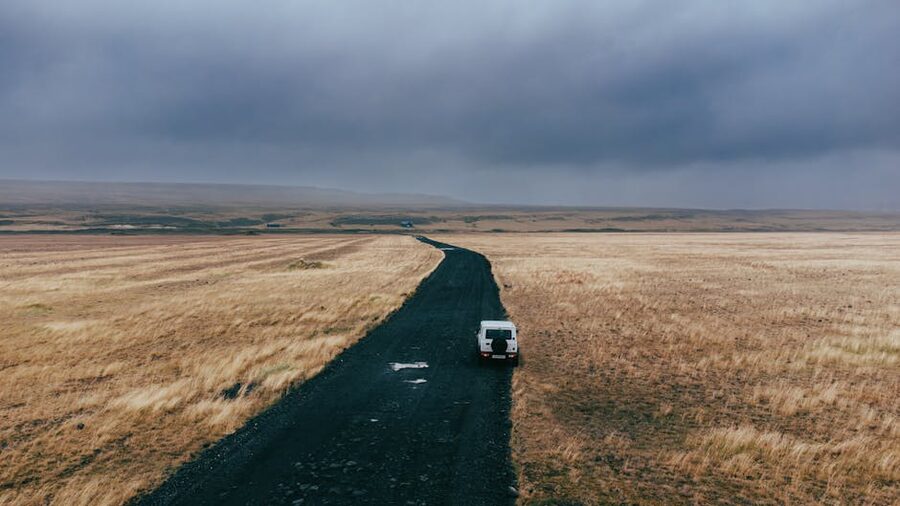Lone vehicle on a rugged road in Iceland's vast overcast landscape