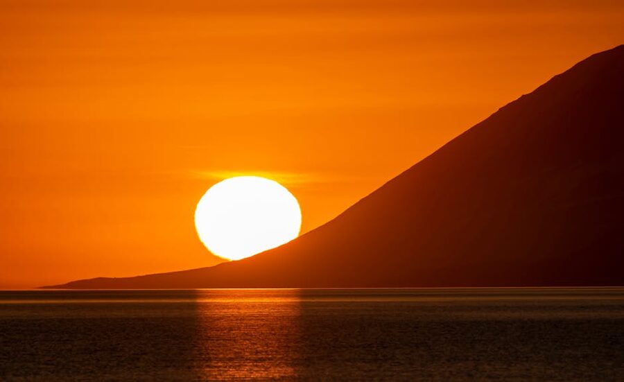 Iceland coastline under a low summer sun, golden light over the ocean
