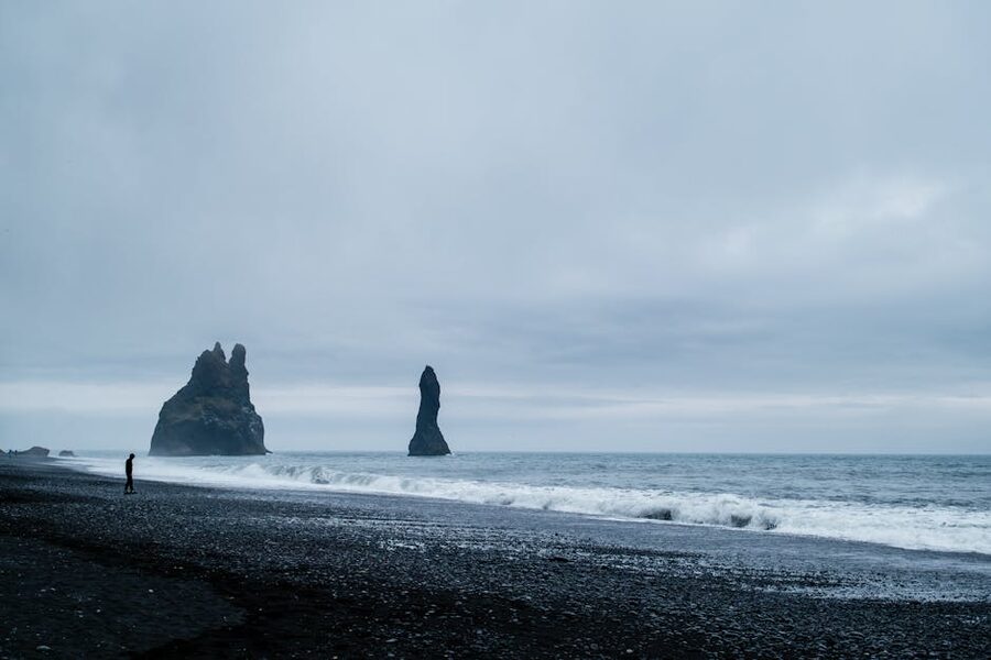 A solitary person on the black sand of Reynisfjara beach near Vik