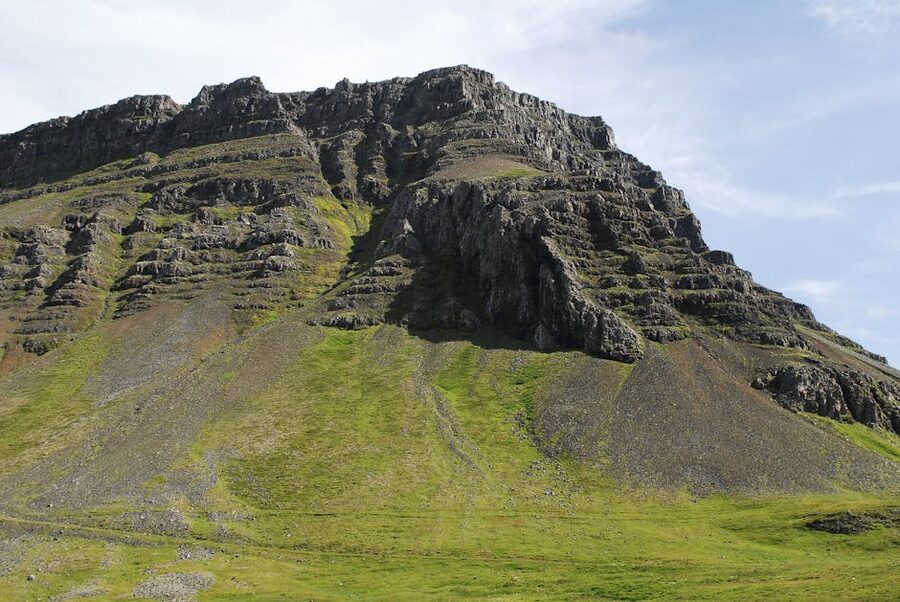 A dramatic Westfjords mountain rising above green pastures, Iceland