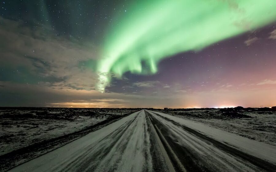 Northern lights over a snowy road in Iceland in winter