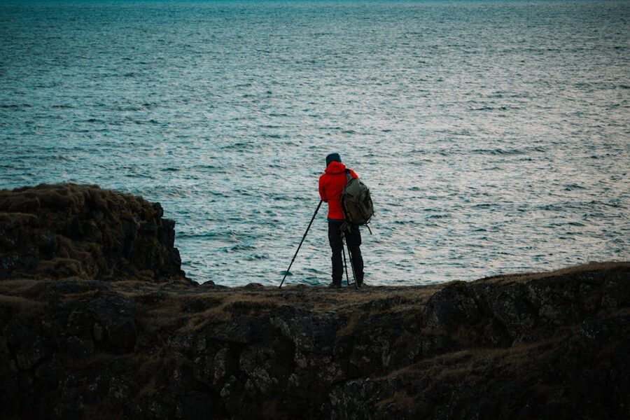Photographer in red jacket capturing Iceland coastal scene