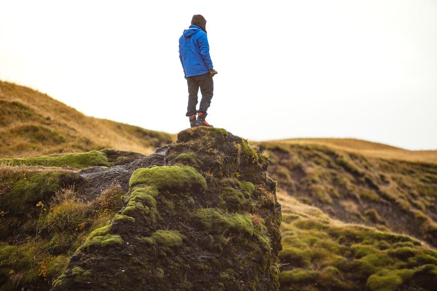 Walker in waterproof hiking boots on moss-covered Icelandic cliff