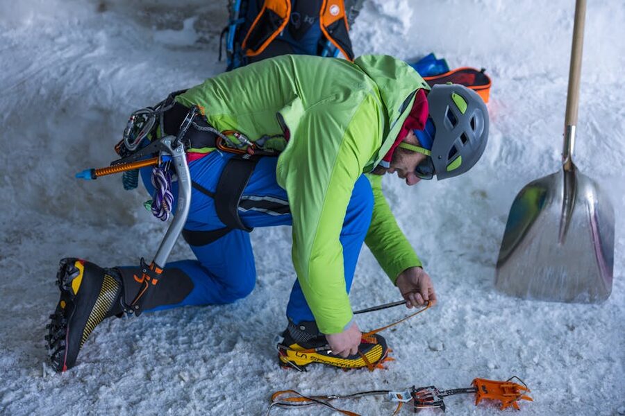Climber adjusting traction crampons on icy ground