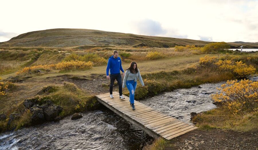 Hikers walking across a bridge in Kirkjubaejarklaustur in summer