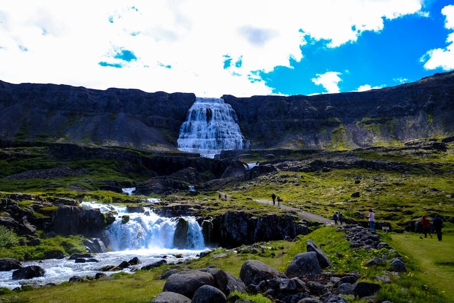 Dynjandi waterfall cascading down a rocky cliff in summer light