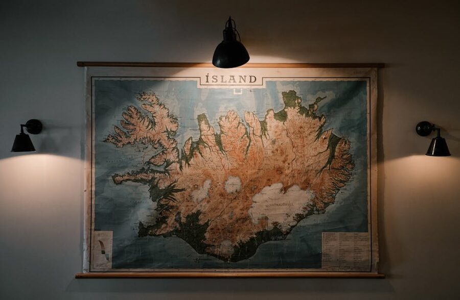 A paper map of Iceland on a hostel wall, lit by a lamp