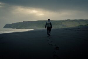 Lone traveler walking on the black sands of Vik in Myrdal, south Iceland