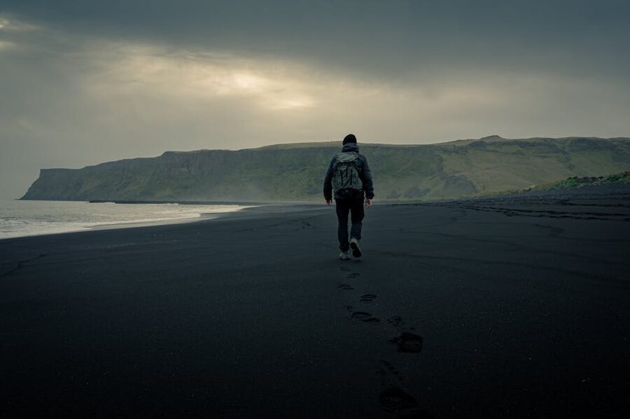 Lone traveler walking on the black sands of Vik in Myrdal, south Iceland
