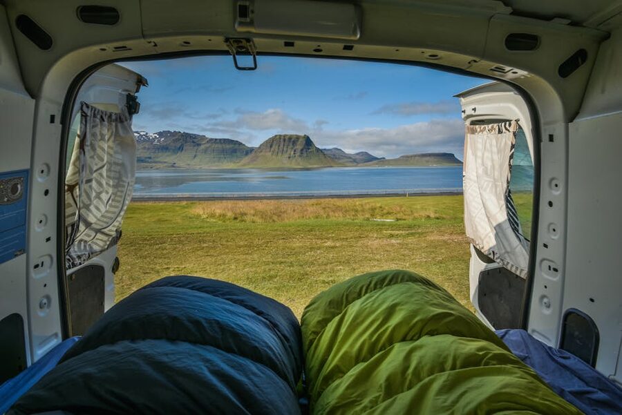 Campervan parked beside a lake with mountains in the background in Iceland