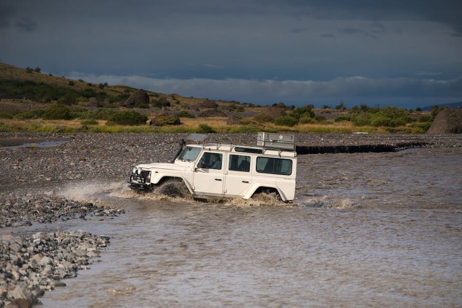 White 4x4 SUV crossing a rocky river in Iceland's rugged highlands