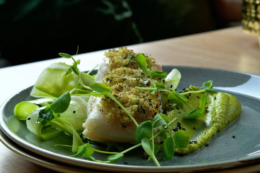 Cod fillet with fennel, green peas, and zucchini puree on a restaurant plate