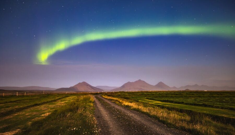 Northern lights stretching across the sky over a road in Iceland