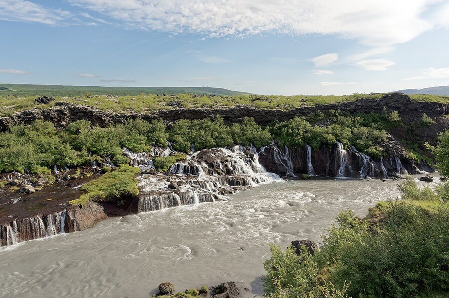 Hraunfossar lava waterfalls flowing out of a black lava field into a river