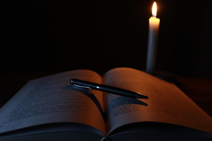Open old book by candlelight in dim library setting