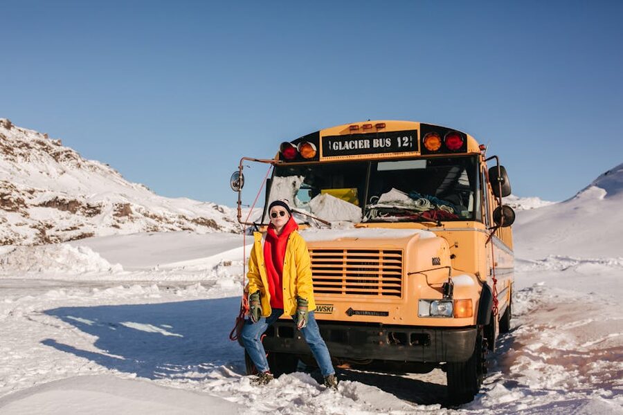 Woman in winter clothing standing beside a glacier tour bus in Iceland