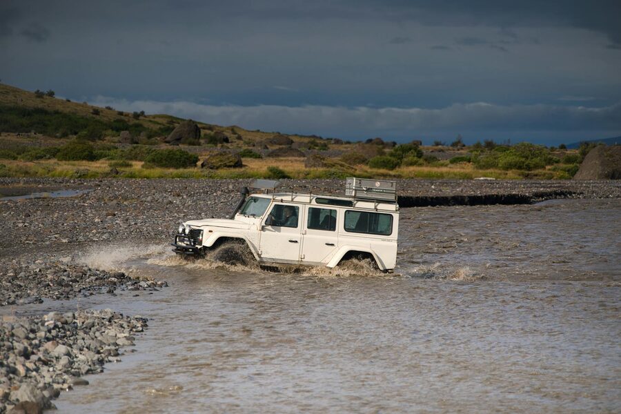 White SUV crossing a glacial river in Iceland highlands