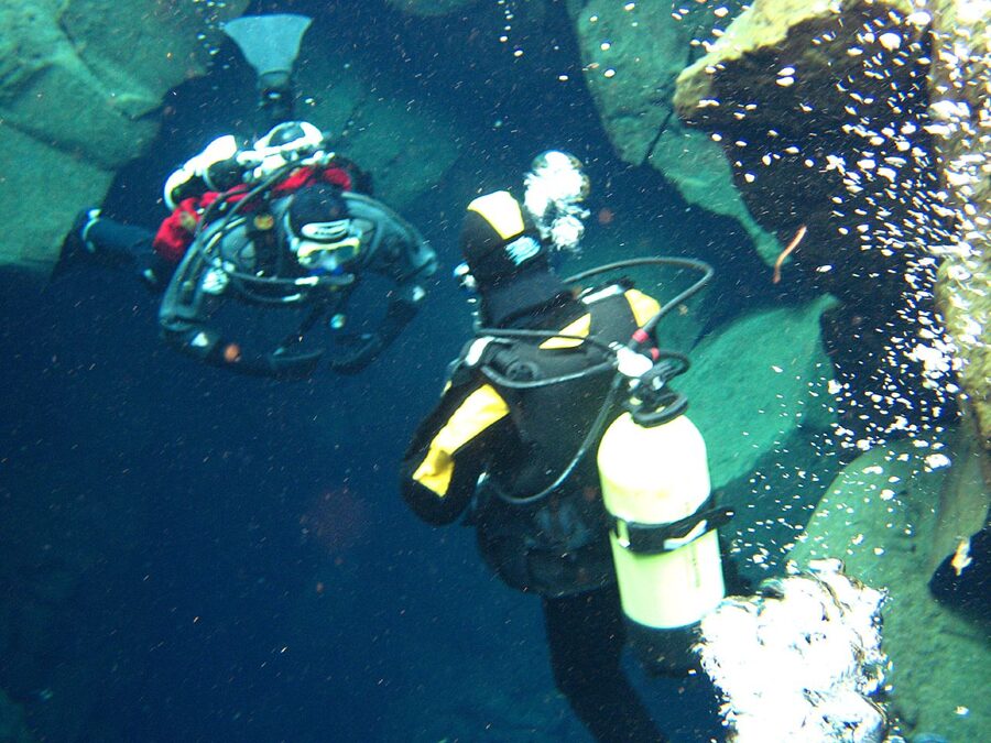 Divers in the Silfra fissure with bubbles rising to the surface