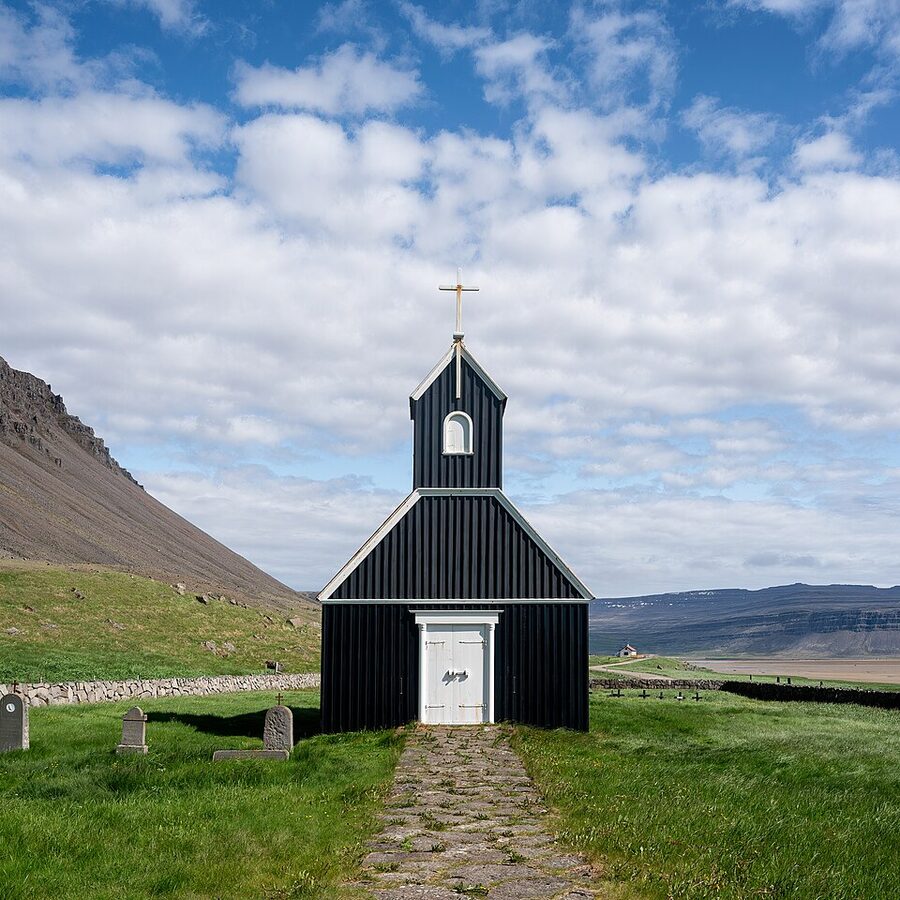 Raudasandur pink sand beach with black church Westfjords Iceland