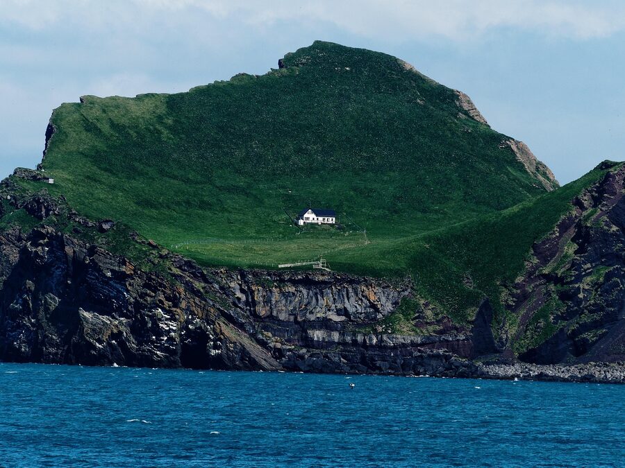A house and the cliffs at Vestmannaeyjar, Iceland